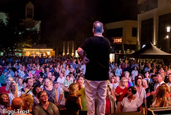 Foto von der Bühne zum Publikum, während der Sänger von NBC das Publikum mit seiner Darbietung fesselt.
